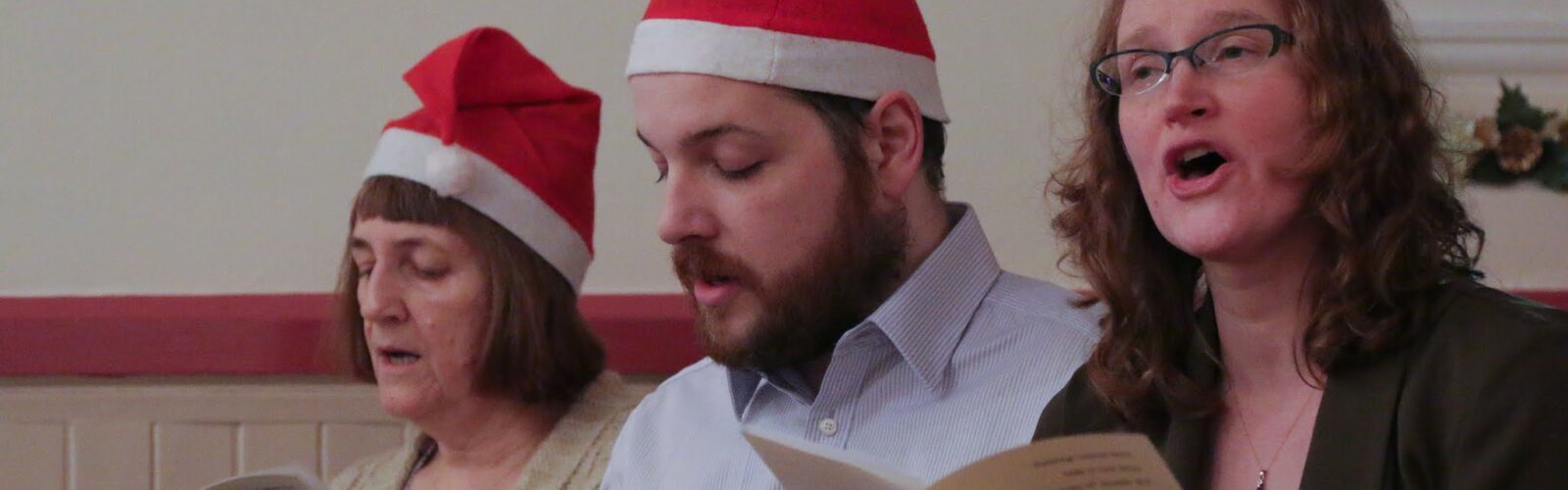 People in Santa Hats enjoying singing carols.